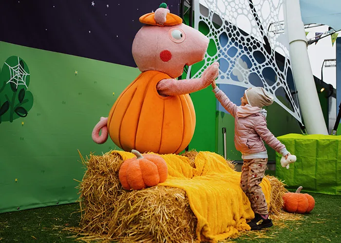 Peppa Wutz im Kürbis-Kostüm mit Kind an Halloween im PEPPA PIG Park